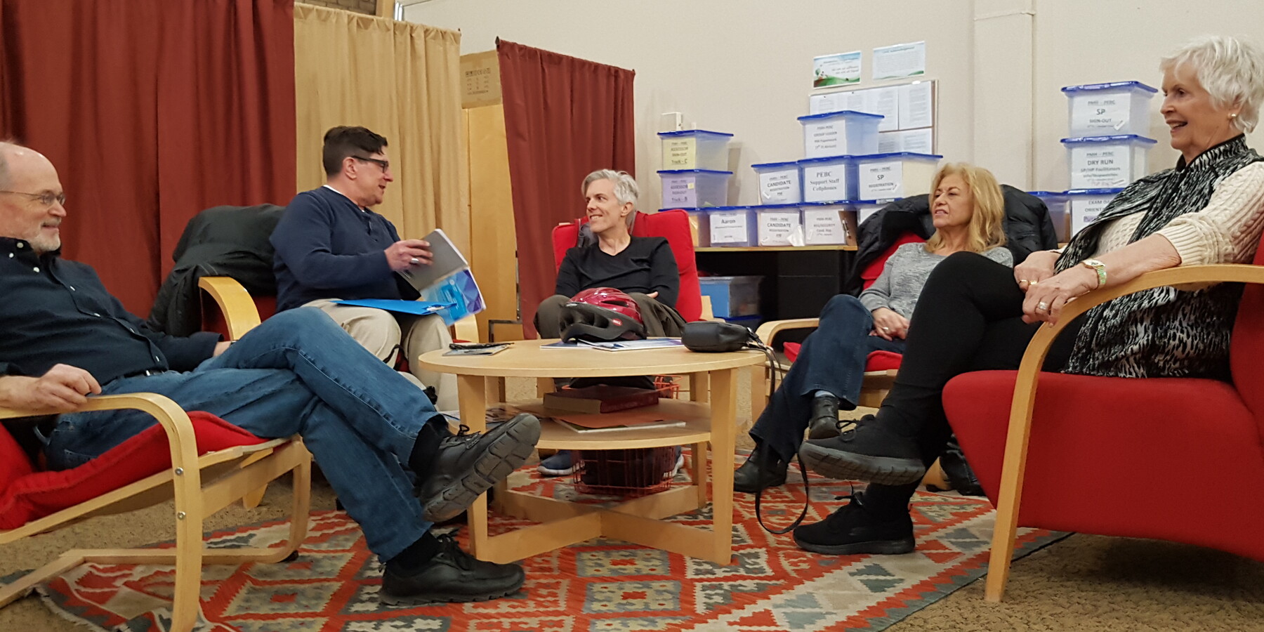 Five people sitting in chairs rehearsing